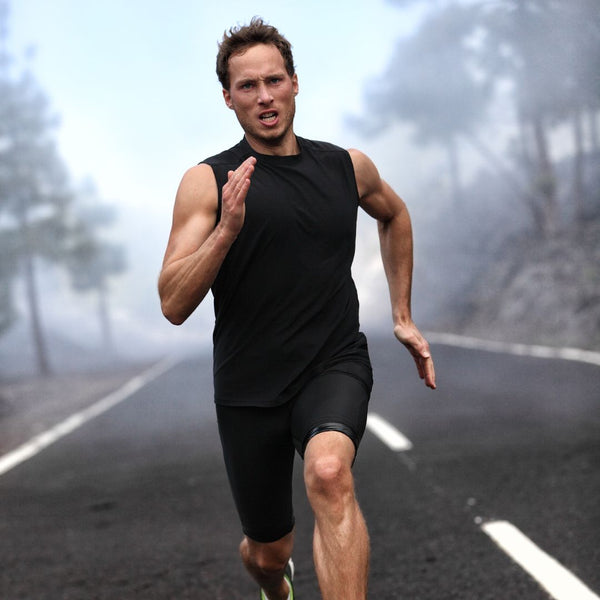 Athletic man running on foggy road in black activewear